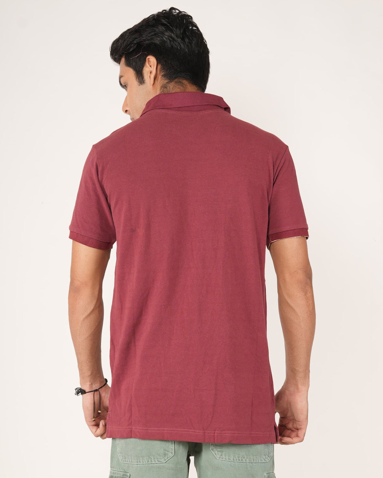 Person wearing a maroon polo shirt and light green cargo pants on a white background