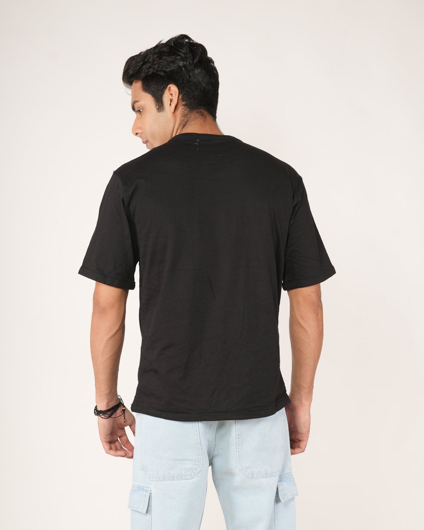 Person wearing a black t-shirt and light blue cargo pants on a white background