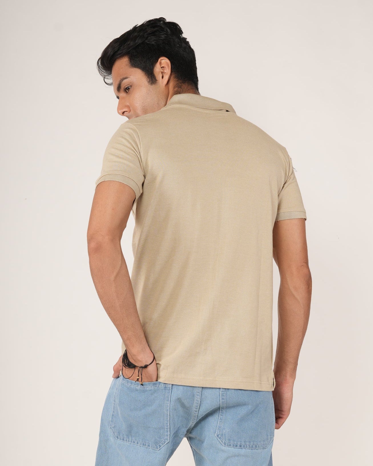 Man wearing Sand/beige polo shirt and light blue jeans.