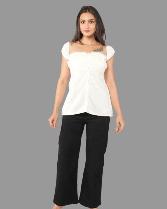 A woman modeling a white short-sleeve top with a ruffled off-the-shoulder neckline and front button placket, paired with black pants.