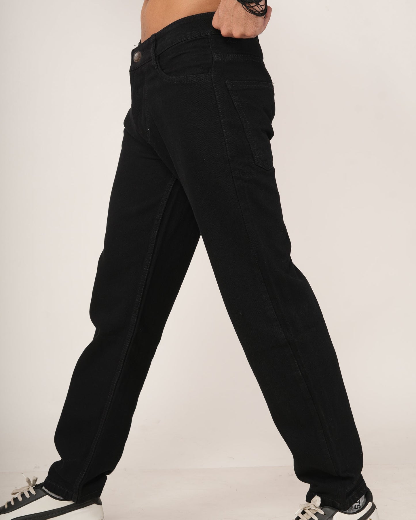 Person wearing black relaxed fit jeans and black and white sneakers.
