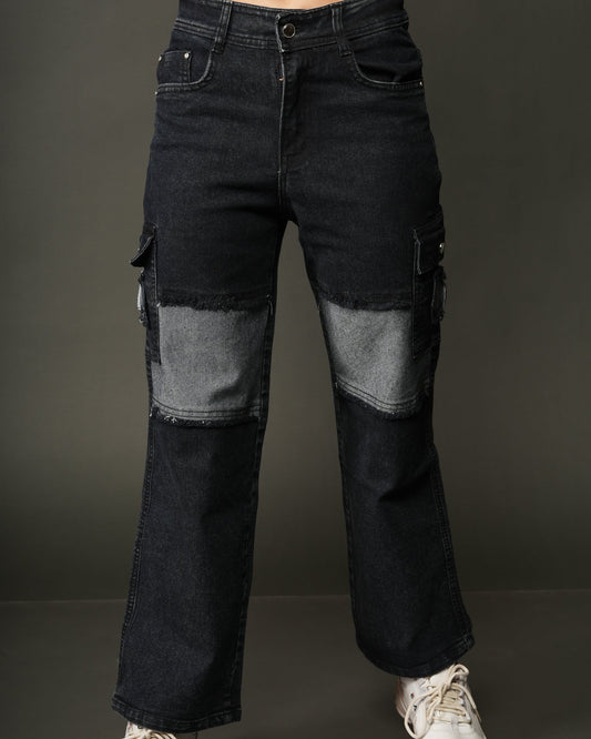 A person wearing dark indigo cargo flare jeans with light gray patchwork knee panels, styled with a white cropped tie-front top and white sneakers.