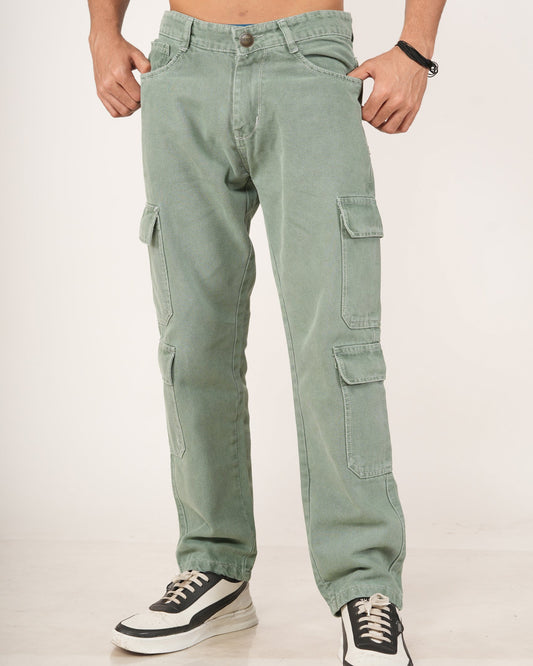 A man wearing sage green 8 pocket cargo jeans, shown from the chest down against a plain light background. He is wearing black and white sneakers.