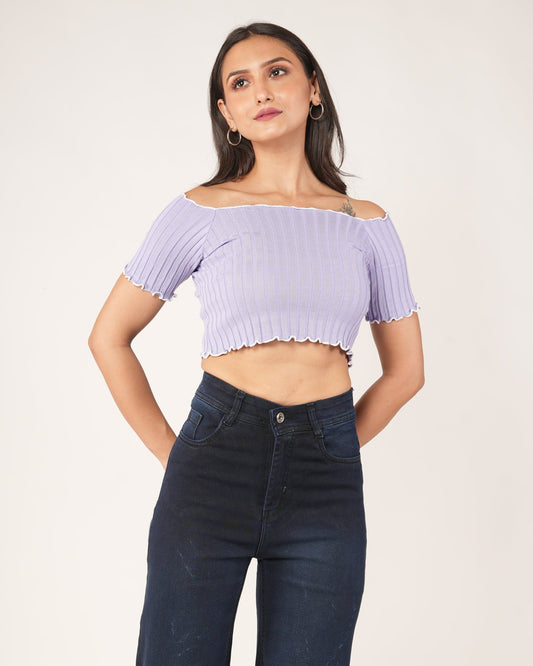 A woman modeling a lavender/light purple off-the-shoulder ribbed crop top with short sleeves and a scalloped hem, paired with dark blue jeans.
