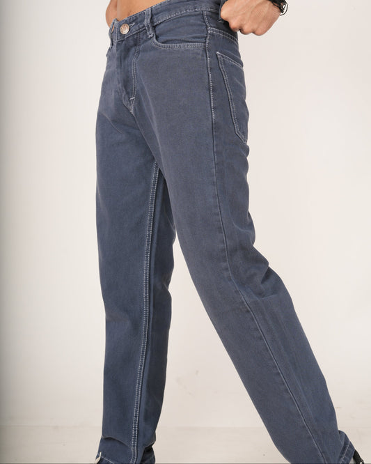 A person modeling a pair of slate blue straight-fit jeans with black and white sneakers.