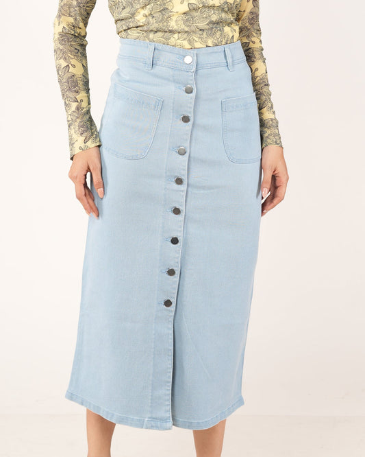 A woman modeling a light blue denim midi skirt with a front button closure.