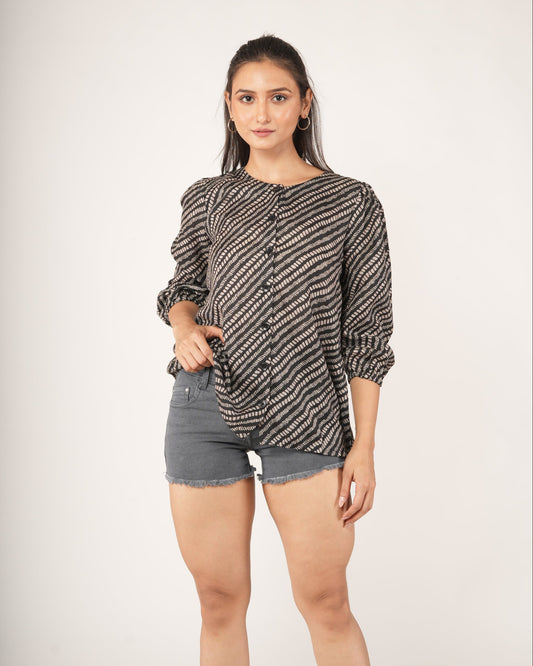 Woman wearing a snake patterned top and denim shorts on a plain background