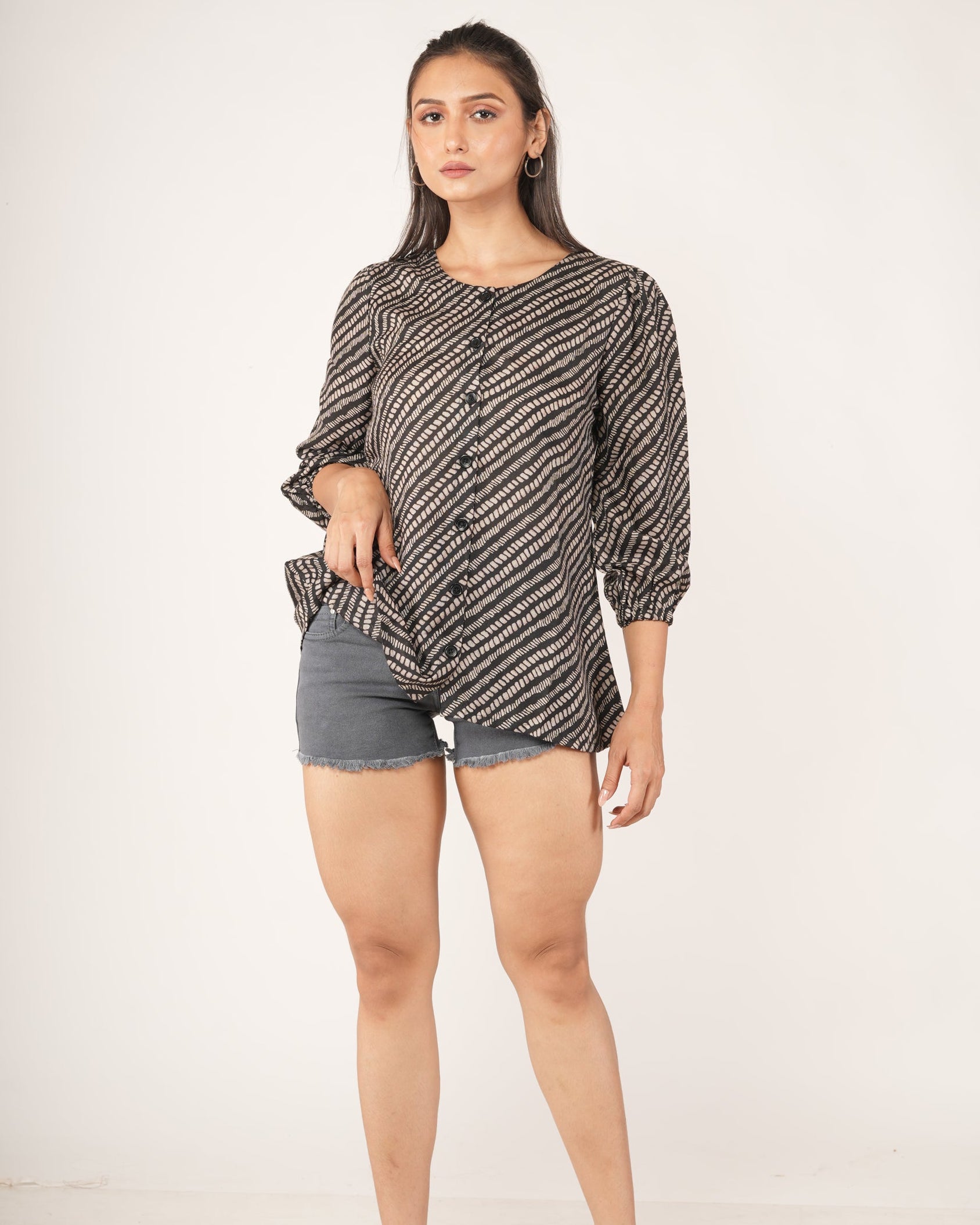 Woman wearing a snake patterned top and gray shorts on a white background