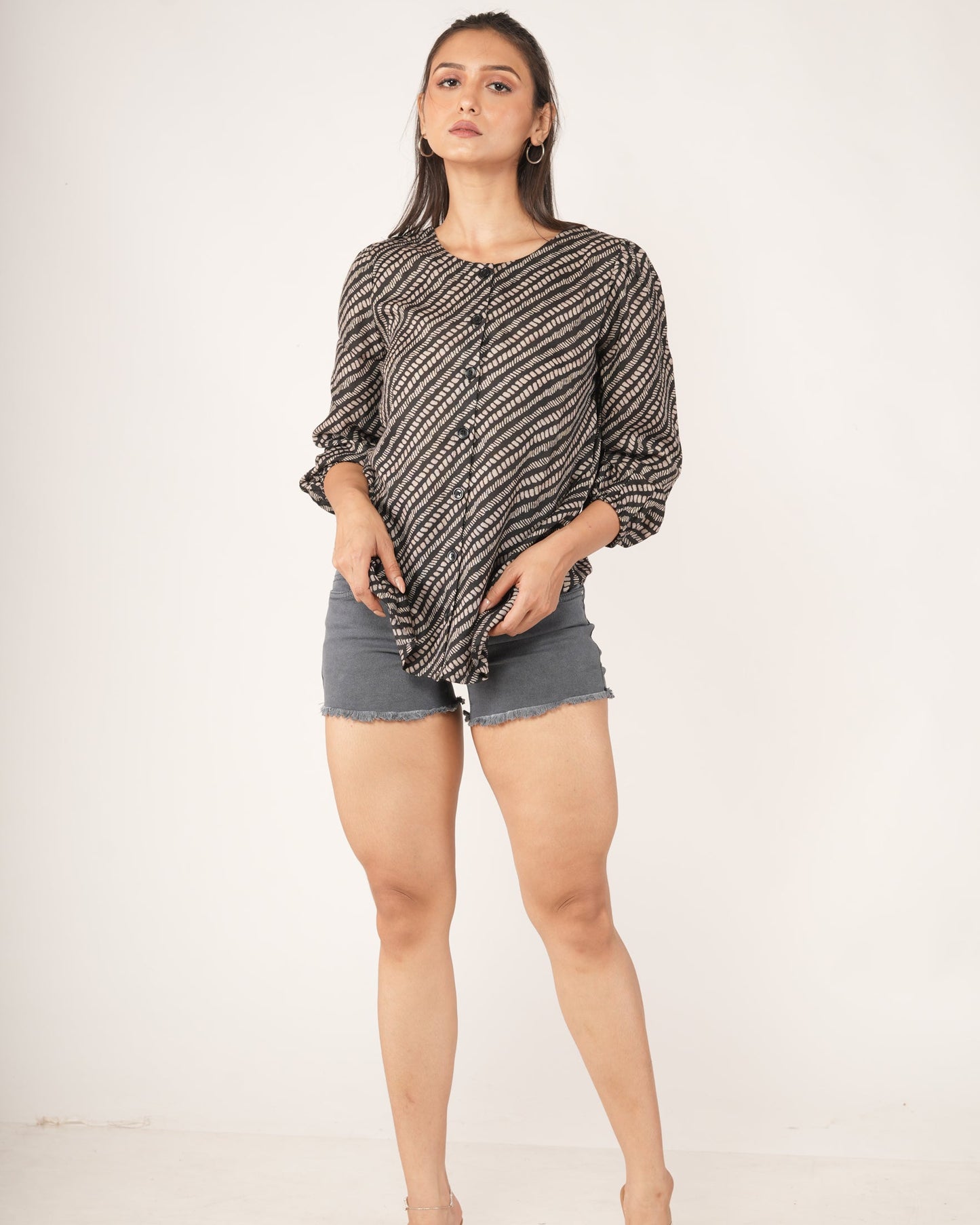 Woman wearing a snake print patterned shirt and gray shorts on a white background