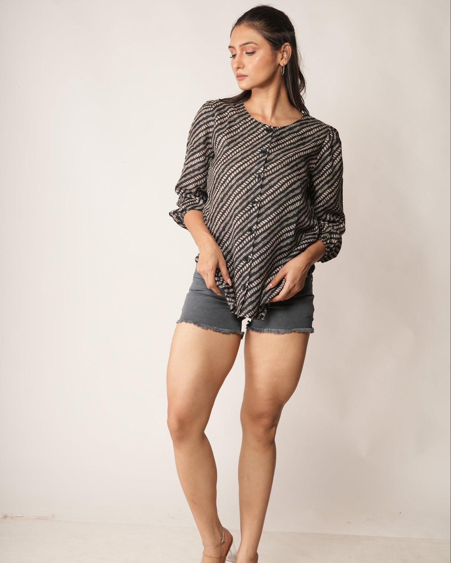 Woman wearing a snake print patterned top and shorts against a plain background