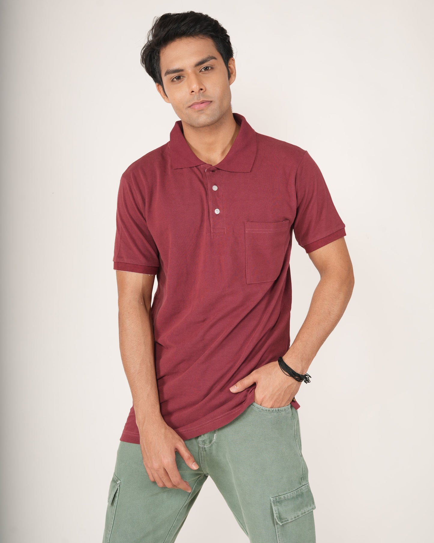 Man wearing a maroon polo shirt and light green pants on a white background