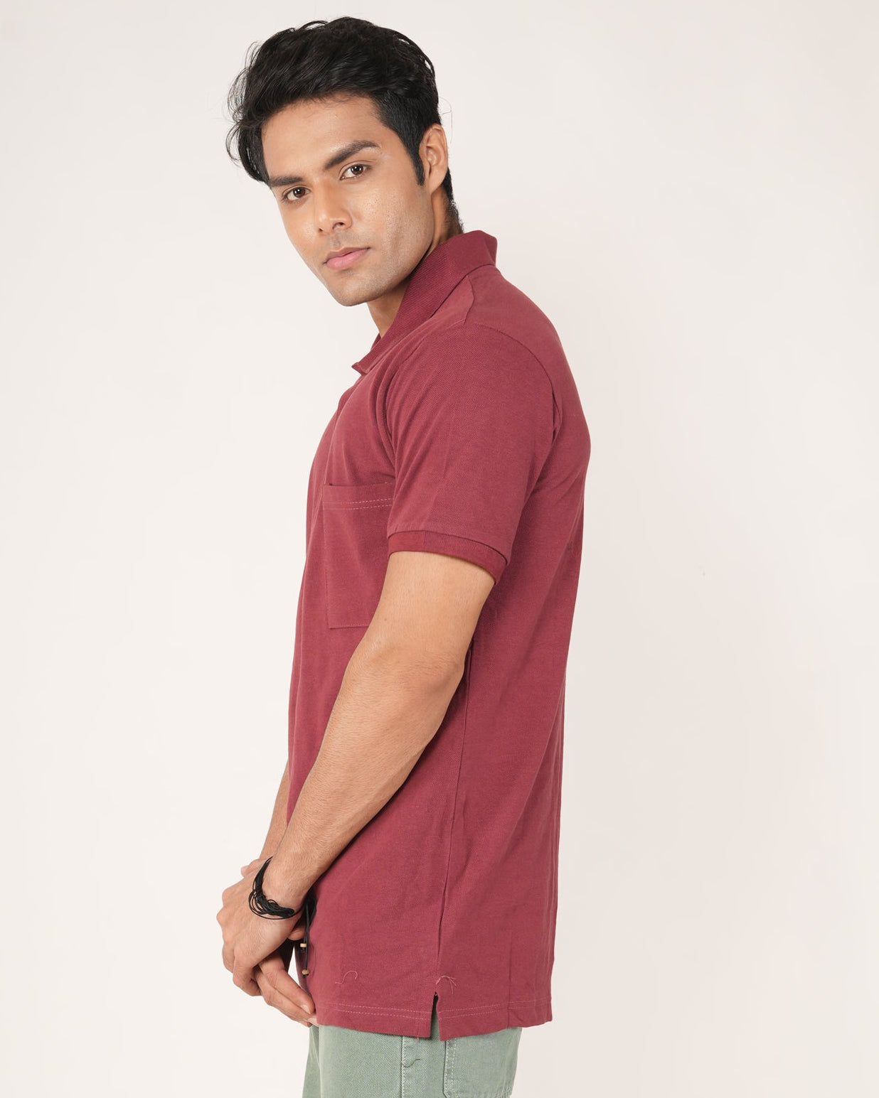 Man wearing a red polo shirt and green pants on a white background