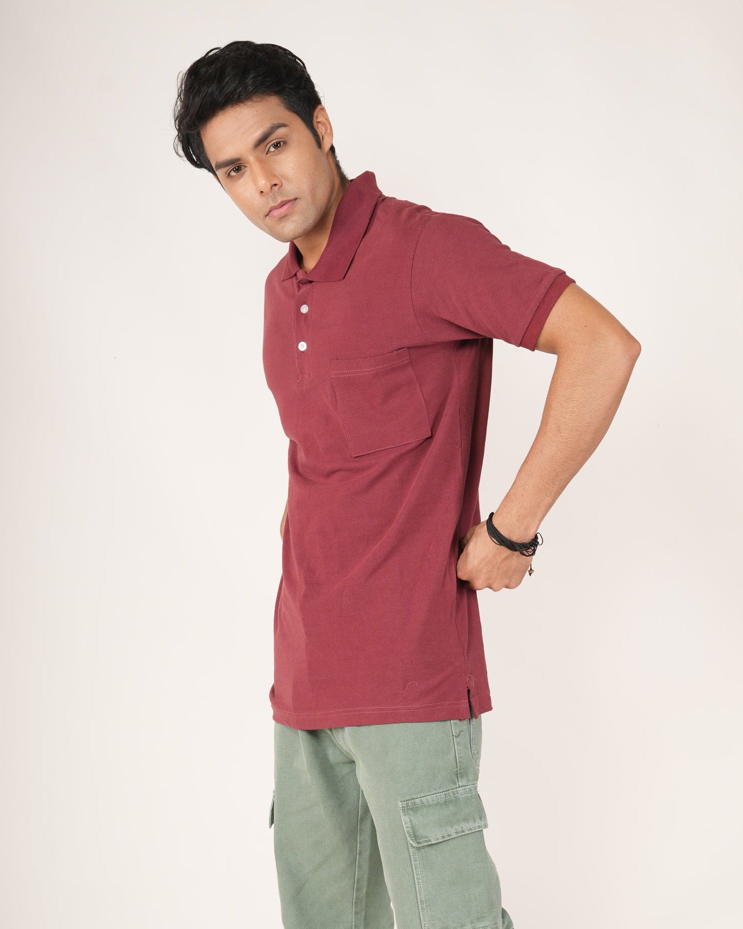 Man wearing a maroon polo shirt and green cargo pants on a white background