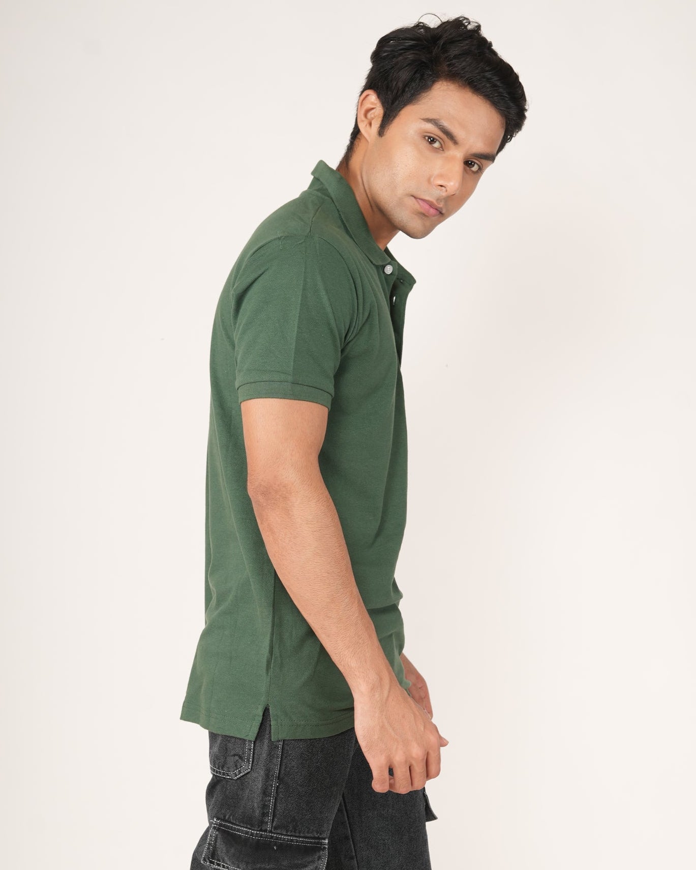 Man wearing a green polo shirt and black pants on a white background