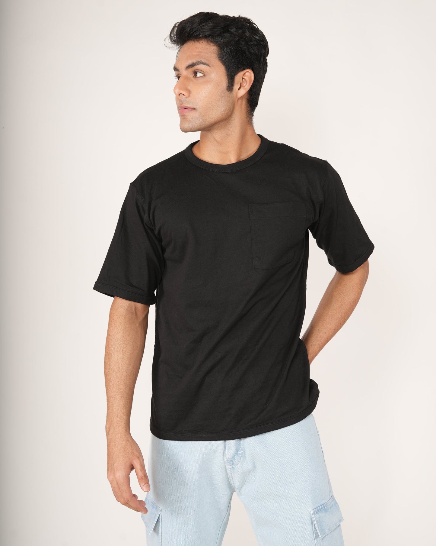 Man wearing a black t-shirt and light blue jeans on a white background