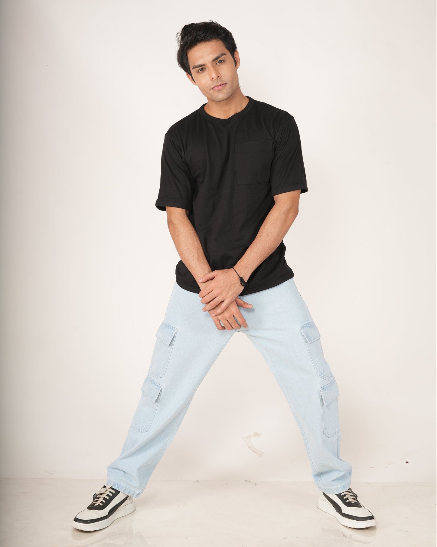 Man wearing a black t-shirt and light blue jeans on a white background
