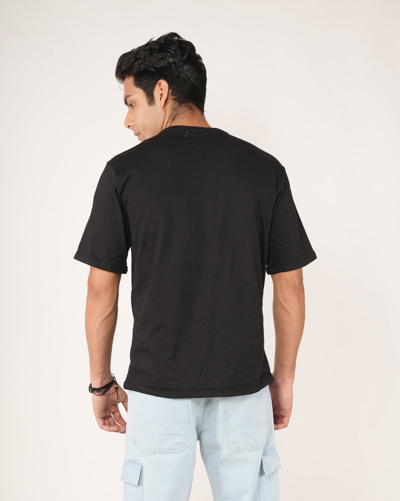 Person wearing a black t-shirt and light blue cargo pants on a white background