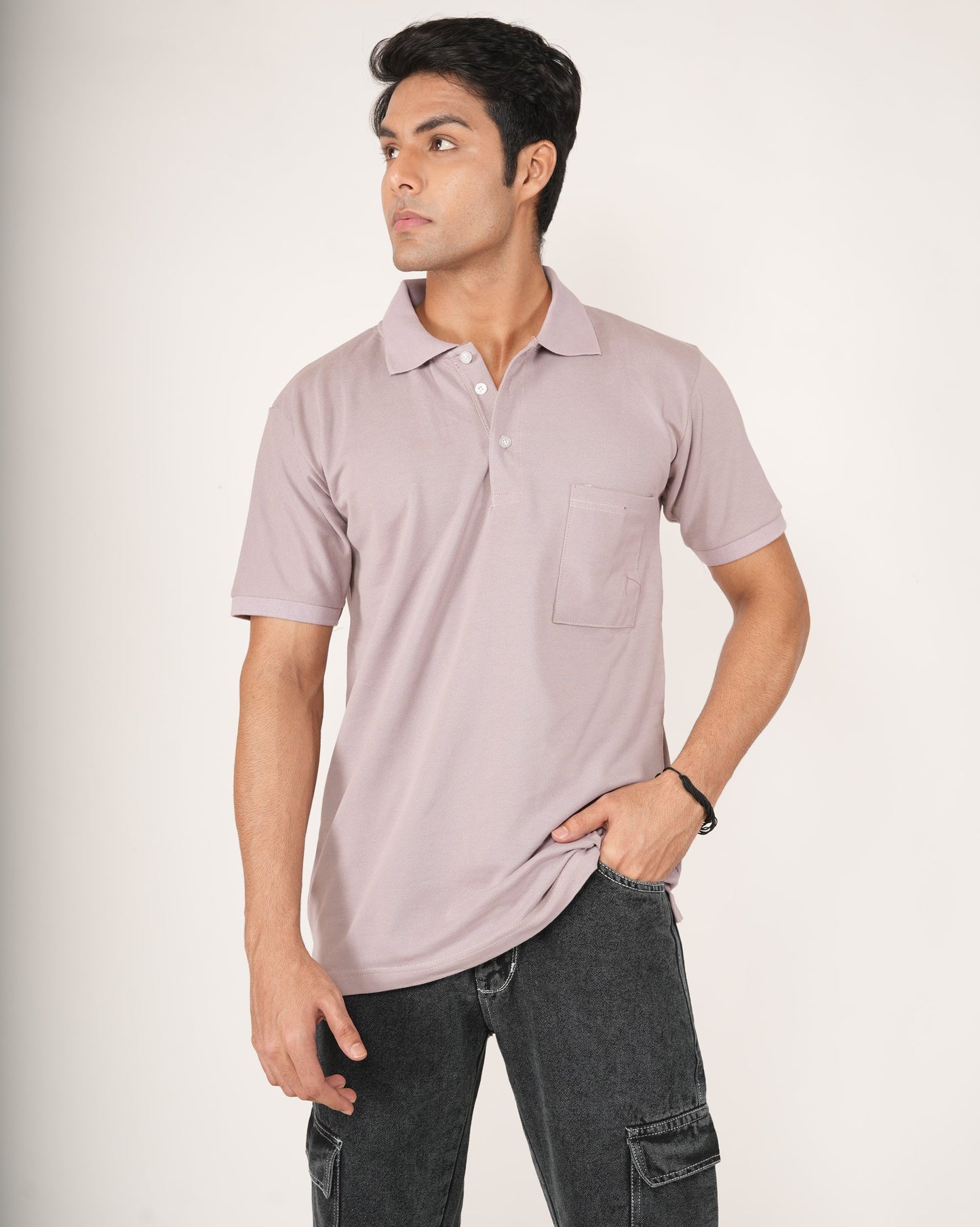 Man wearing a light purple polo shirt and dark jeans on a white background