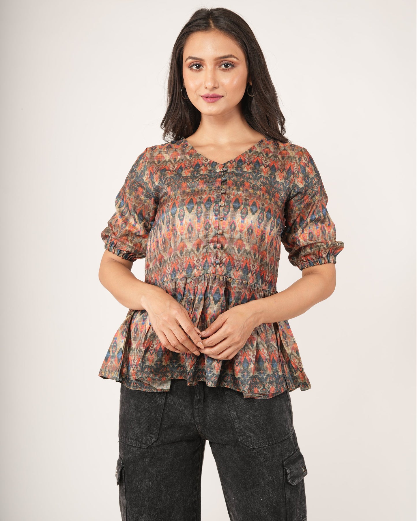 Woman wearing a patterned top and dark pants.