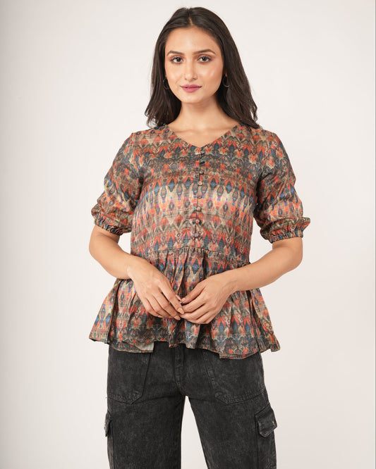 Woman wearing a patterned top and dark pants.