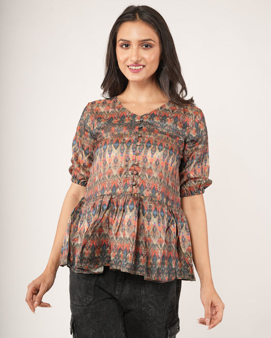 Woman wearing a patterned top and dark pants.
