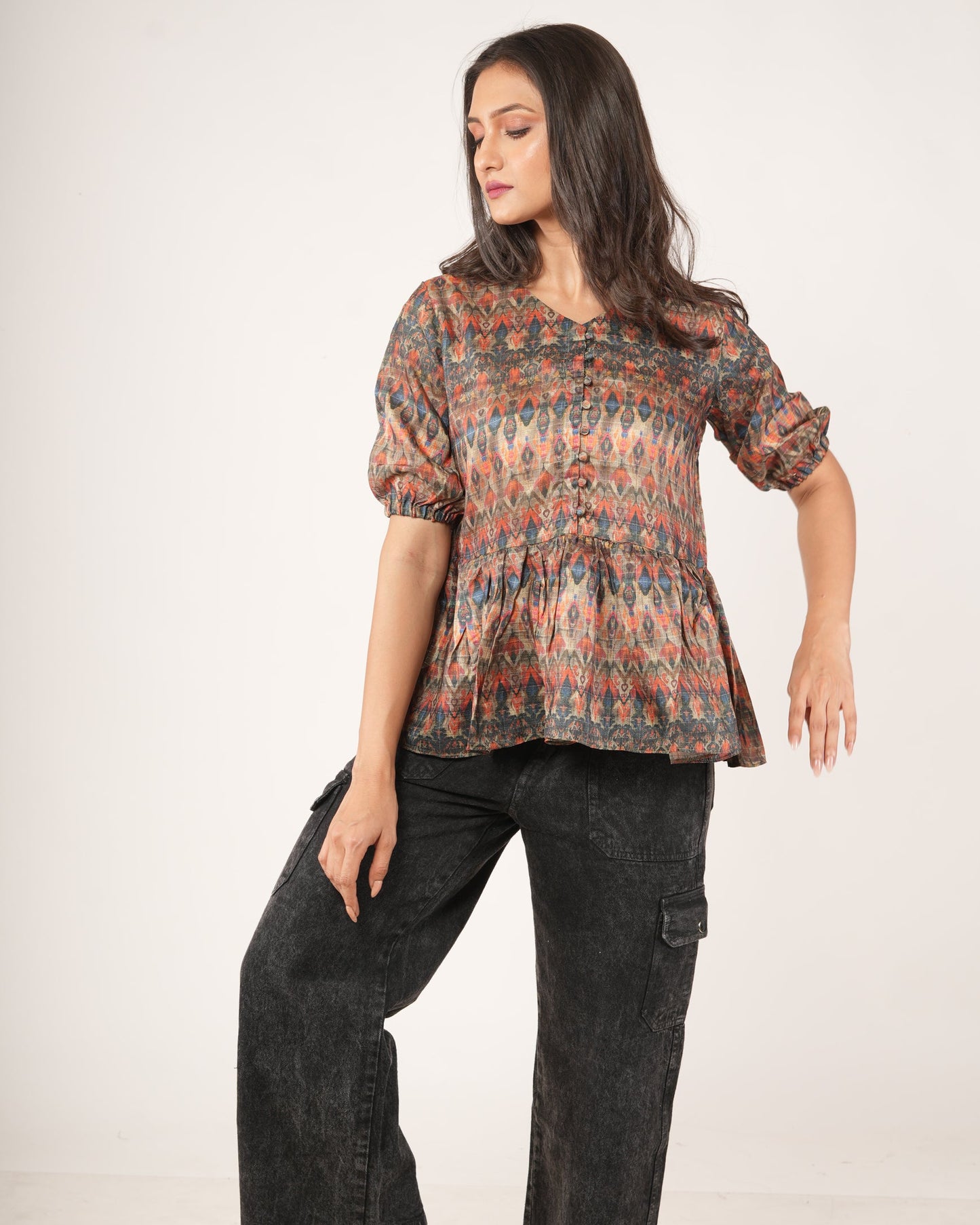 Woman wearing a patterned top and dark pants.