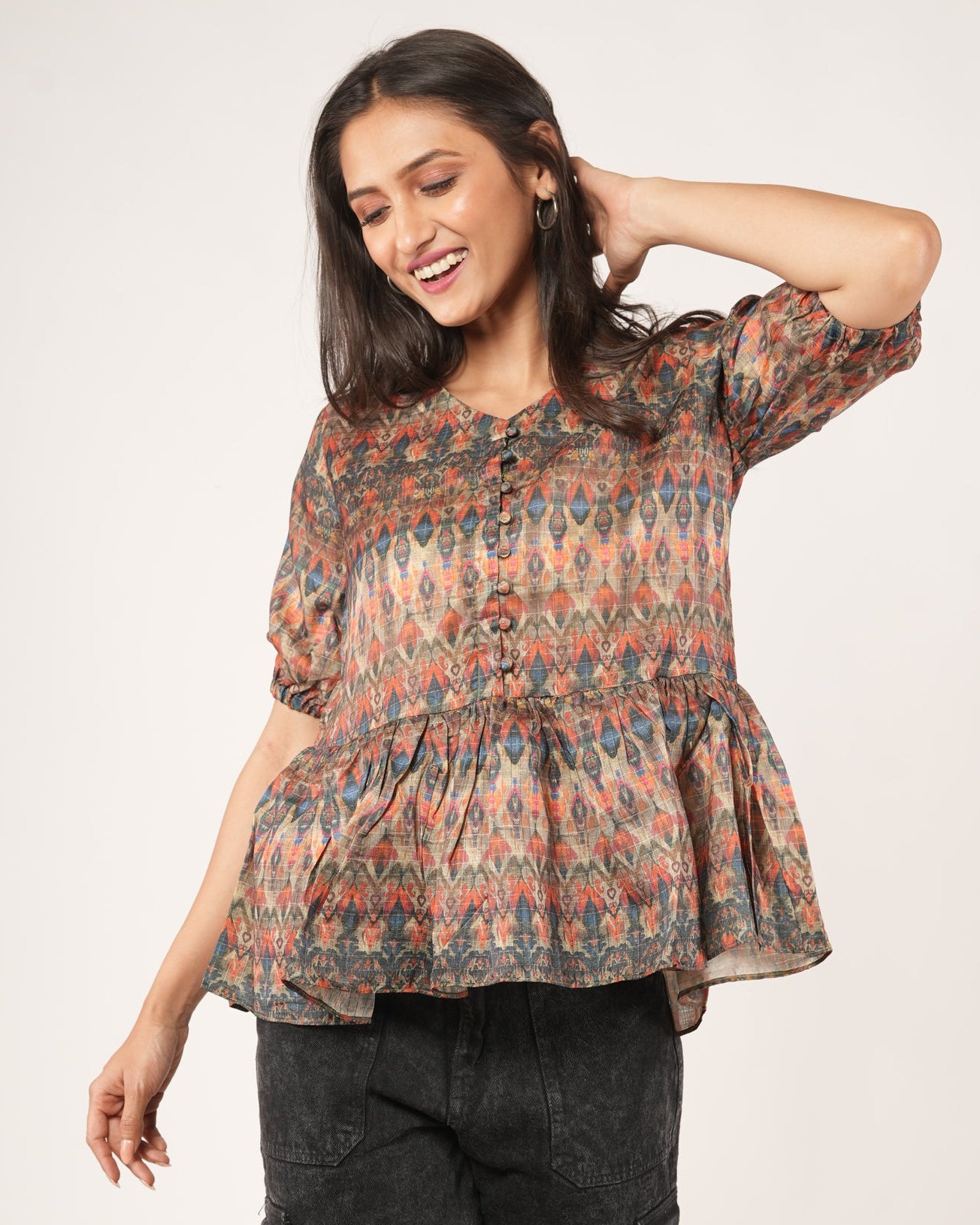 Woman wearing a patterned top and dark pants.