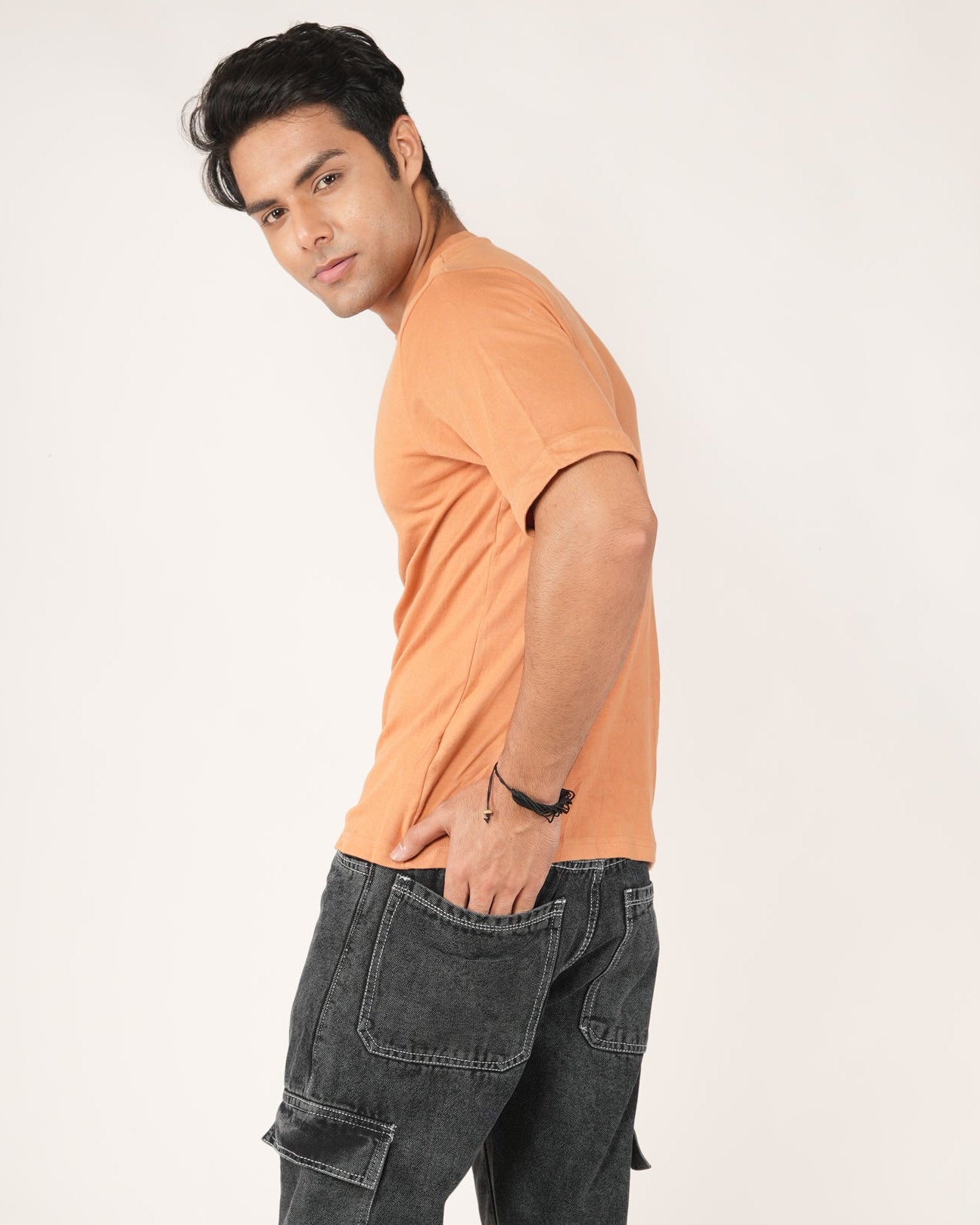 Man wearing an orange shirt and black cargo pants. 