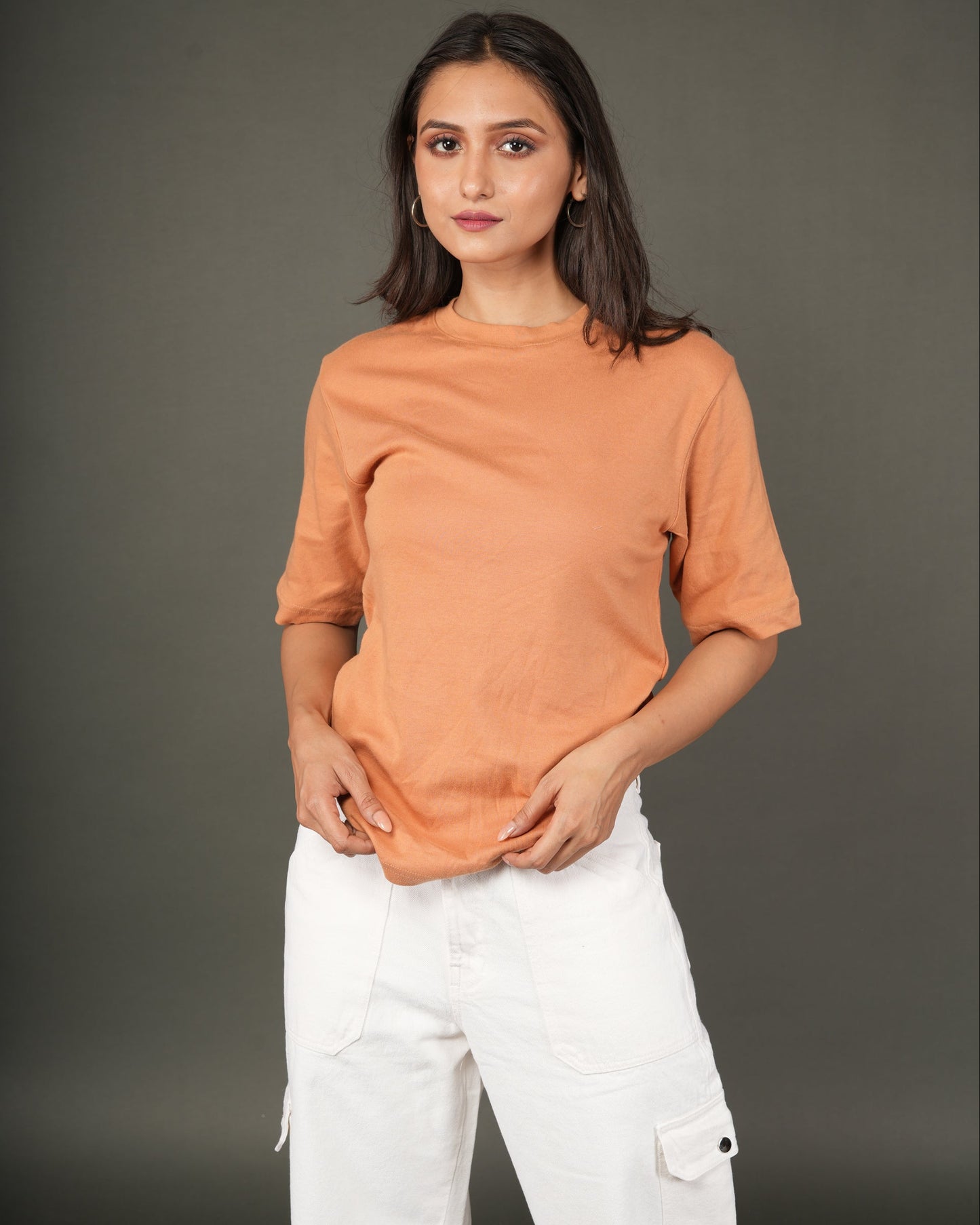 Woman wearing a Peach/orange t-shirt and white pants.