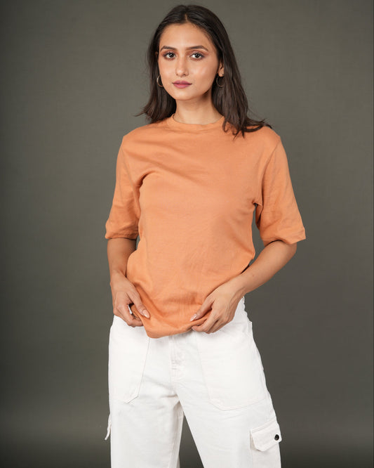 Woman wearing a Peach/orange t-shirt and white pants.