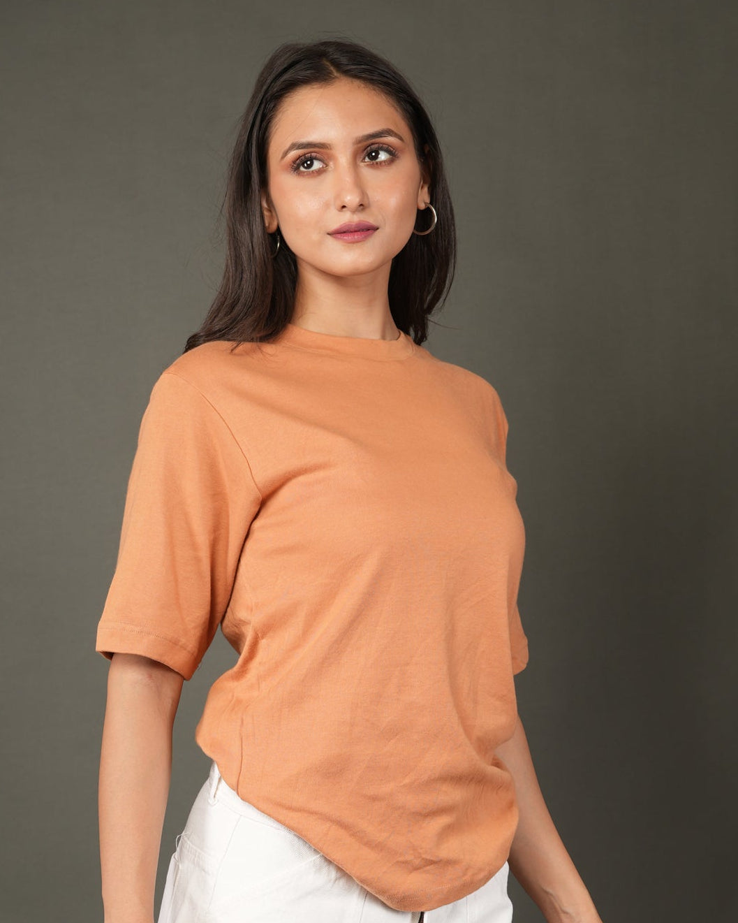 Woman wearing a Peach/orange t-shirt and white pants.