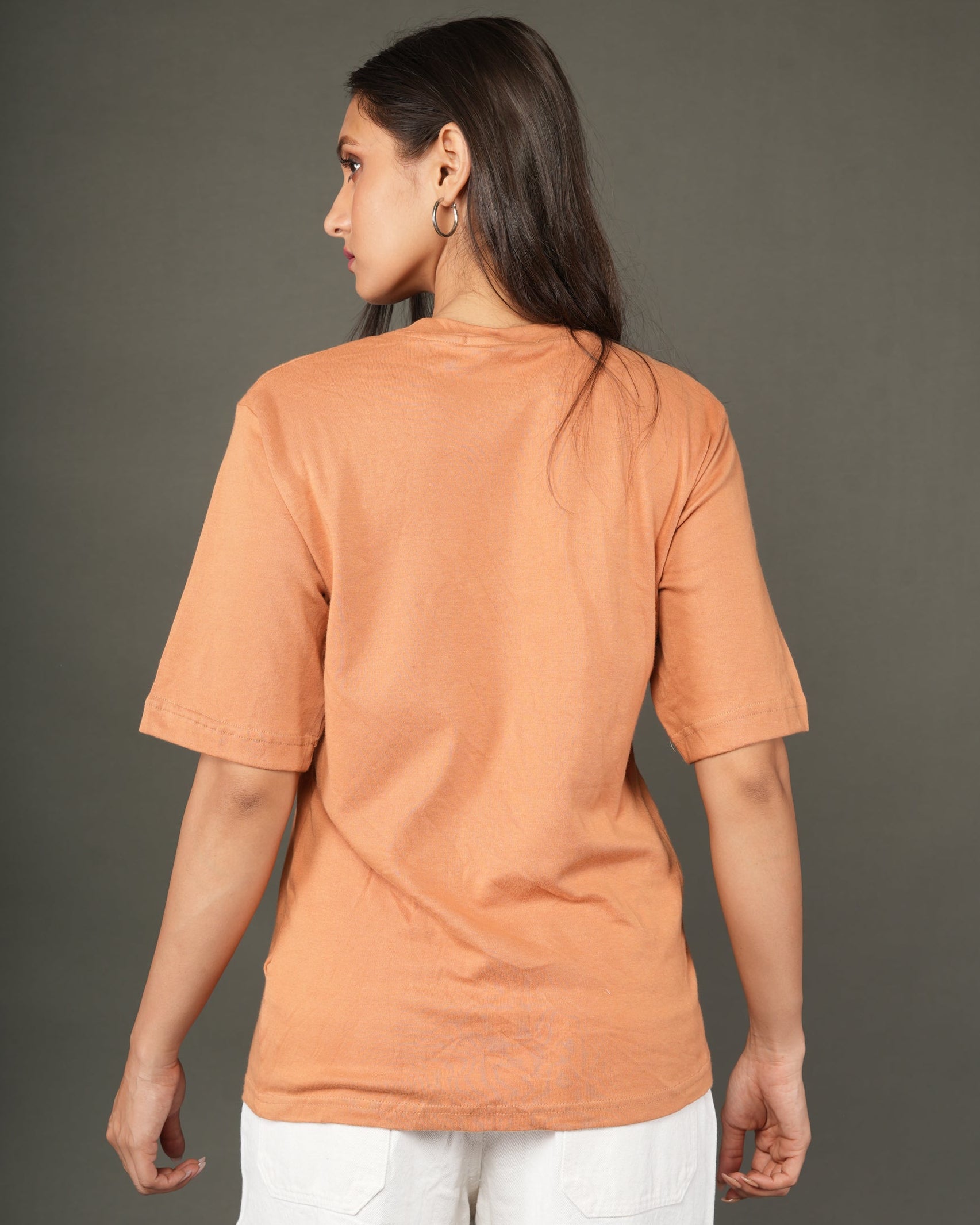 Woman wearing a Peach/orange t-shirt and white pants.