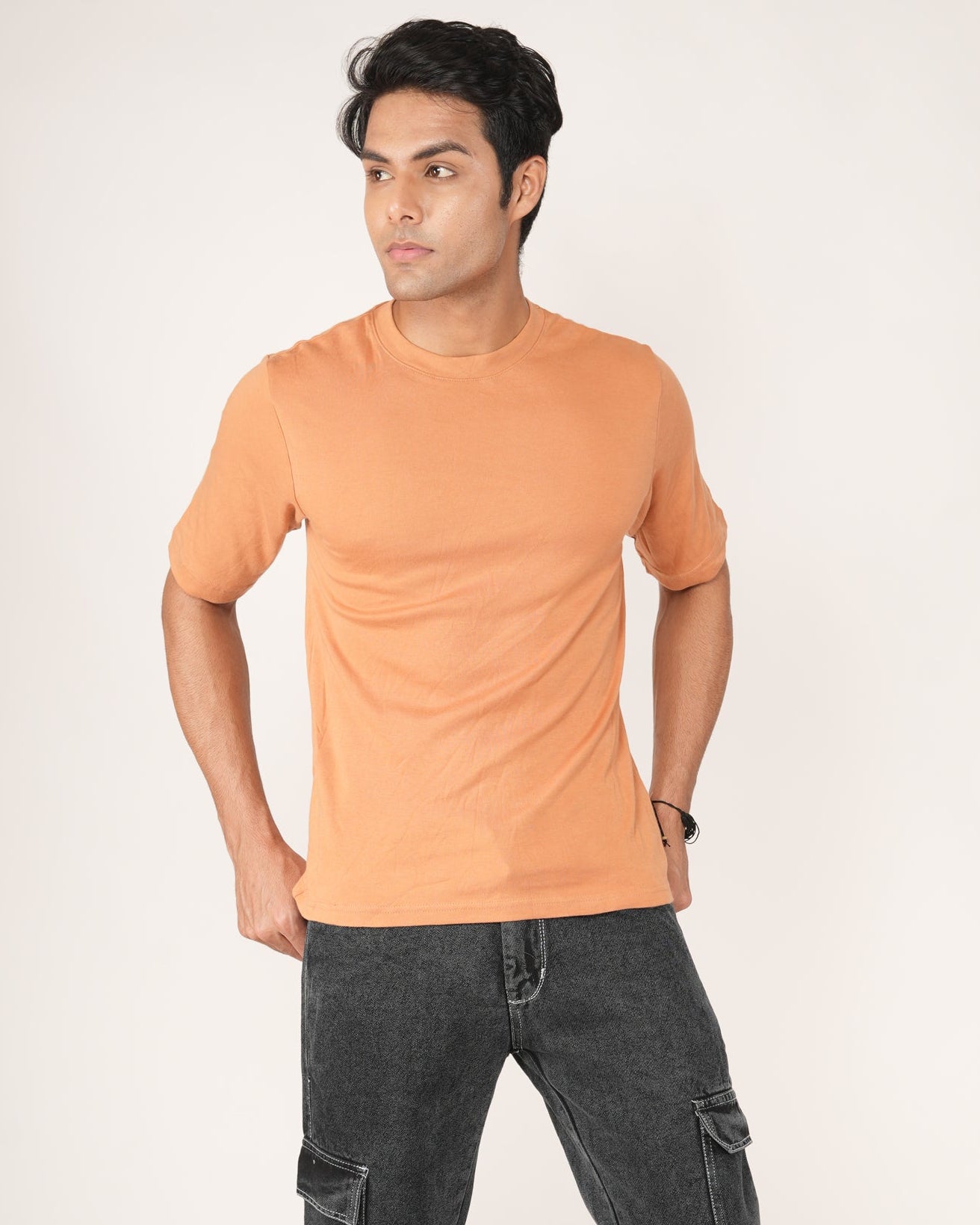Man wearing an peach/orange t-shirt and black jeans.