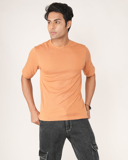 Man wearing an peach/orange t-shirt and black jeans.