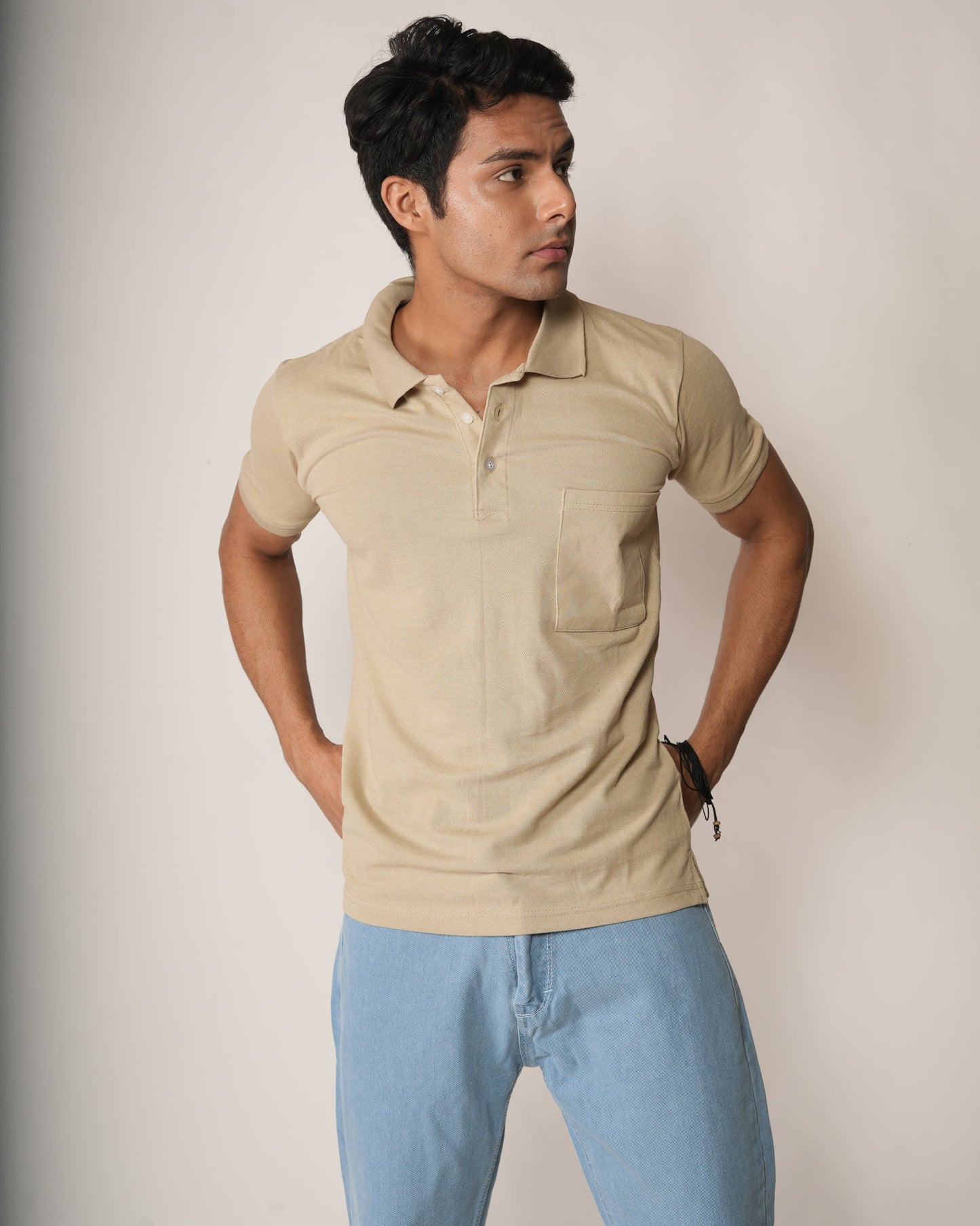 Man wearing a beige polo shirt and light blue jeans.