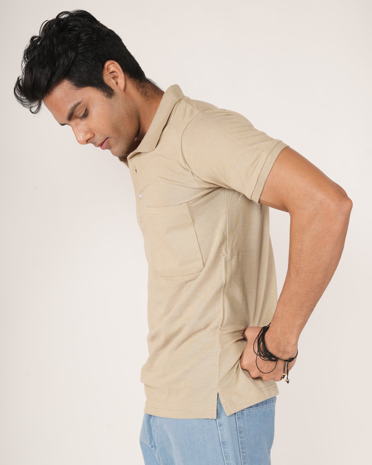 Man wearing a Sand/beige polo shirt and light blue jeans.