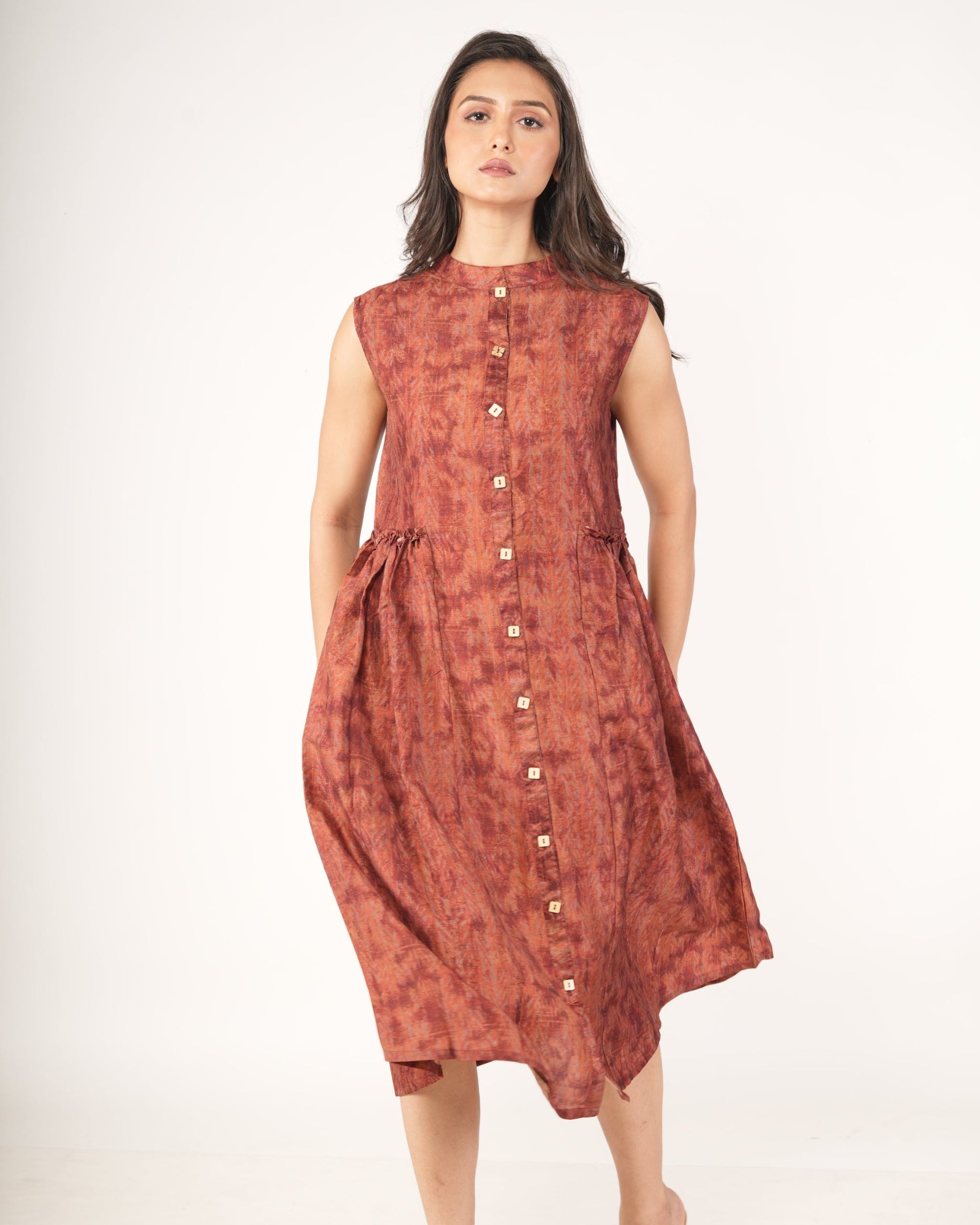 Woman wearing a rust-colored sleeveless dress with buttons.
