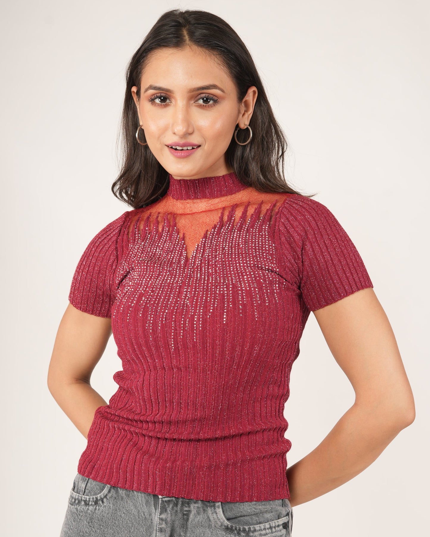 A woman modeling a Short-sleeve Fiesta Red Sheer Mesh Yoke Rhinestone Ribbed Top, paired with gray jeans.
