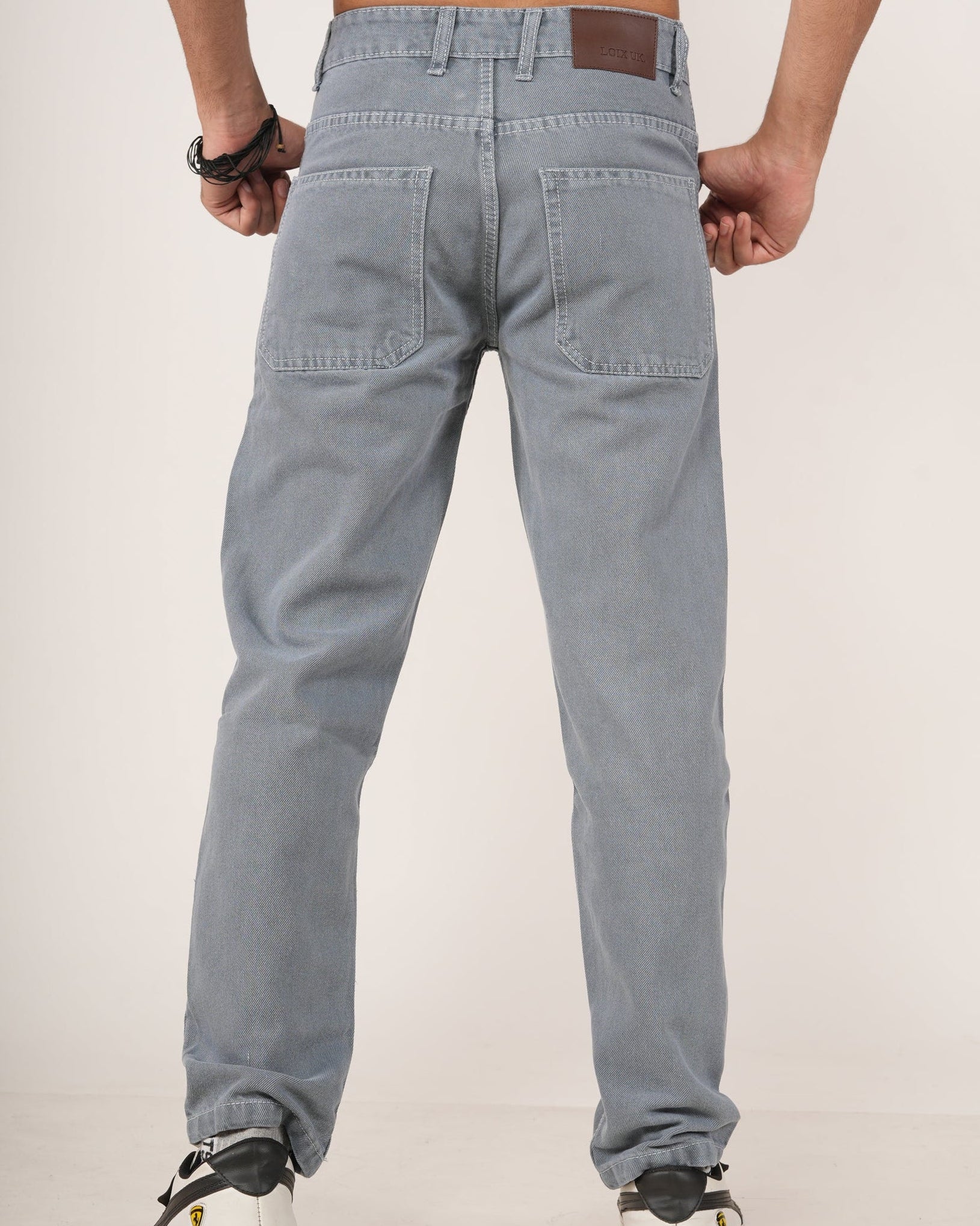 A man wearing Slate Grey Relaxed Straight Jeans, shown from the chest down against a plain light studio background.