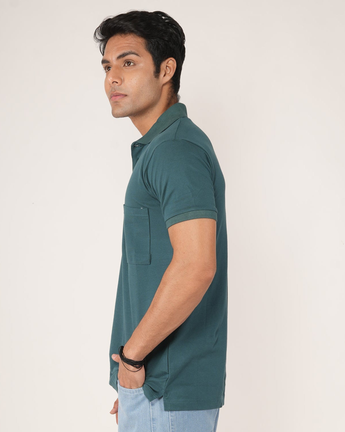Man wearing a teal polo T-shirt and light blue jeans.