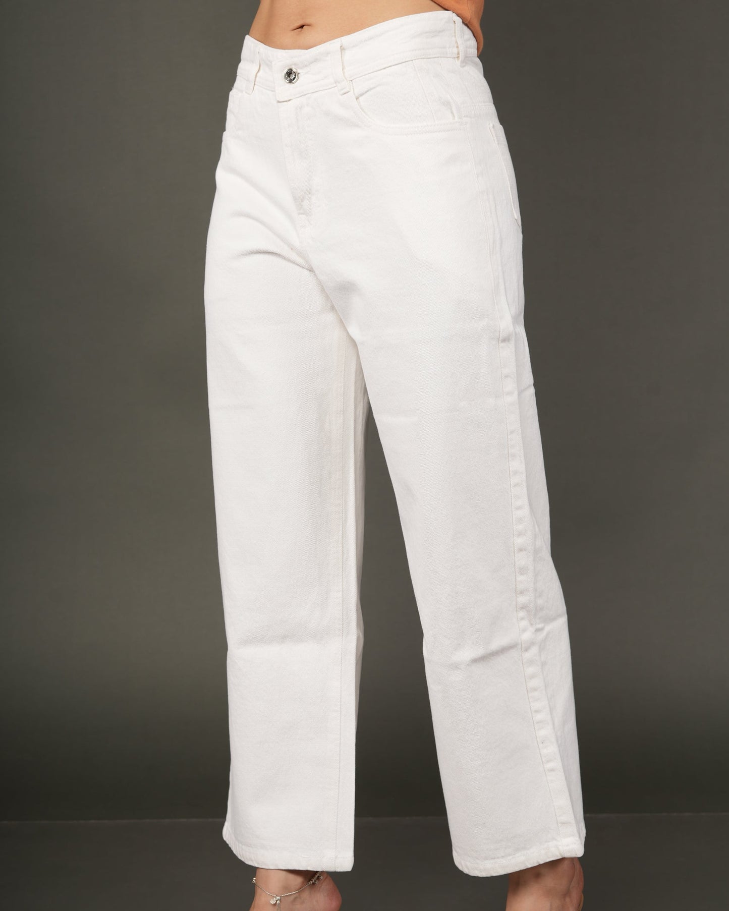 White cropped wide-leg jeans worn by a model, paired with a tied orange top and clear high-heeled sandals.