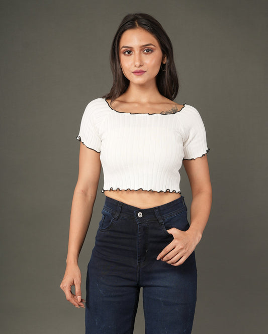 A woman modeling a white short-sleeve ribbed crop top with a scalloped black trim, paired with dark blue jeans.