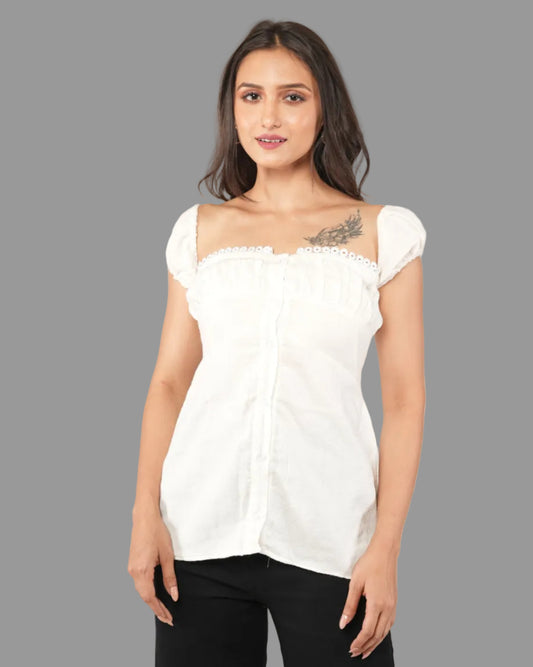 A woman modeling a white short-sleeve top with a ruffled off-the-shoulder neckline and front button placket, paired with black pants.