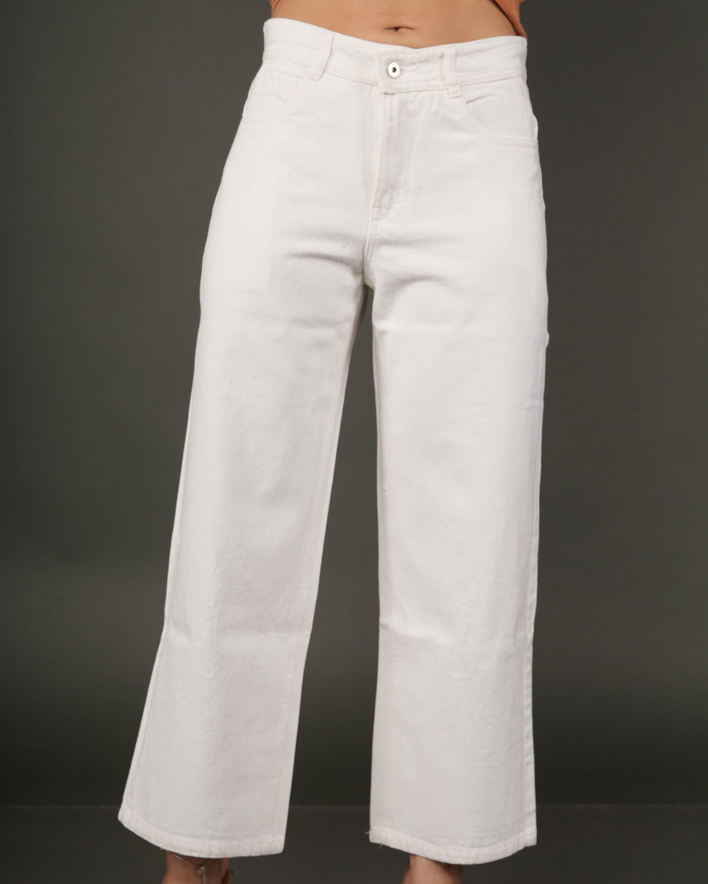 White wide-leg cropped jeans worn by a model, paired with a tied orange-brown top and clear-strap heels.