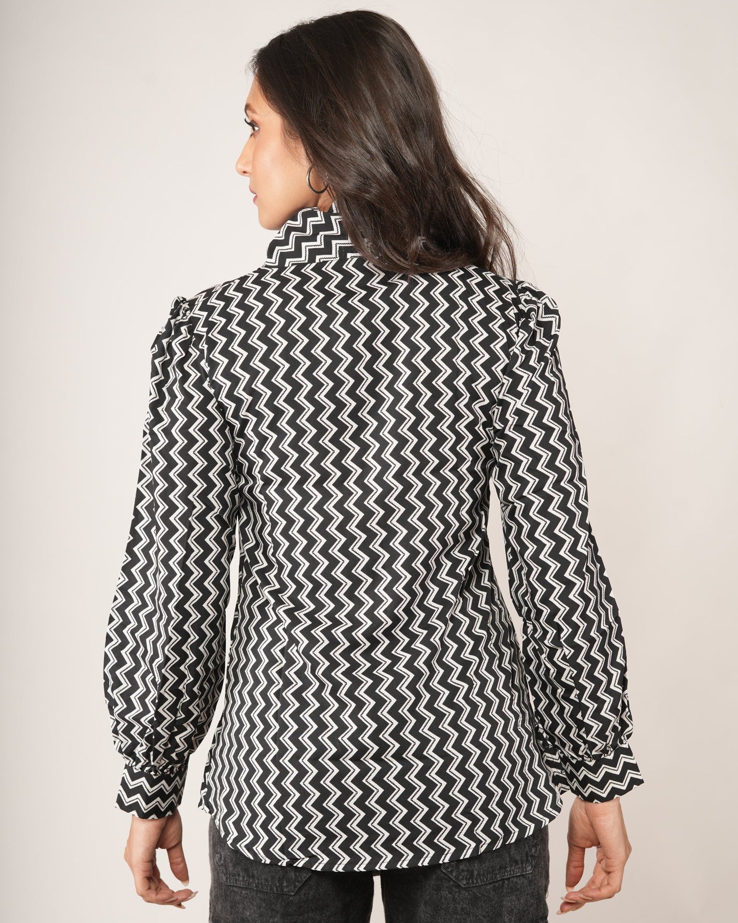 Person wearing a black and white patterned shirt with long sleeves.