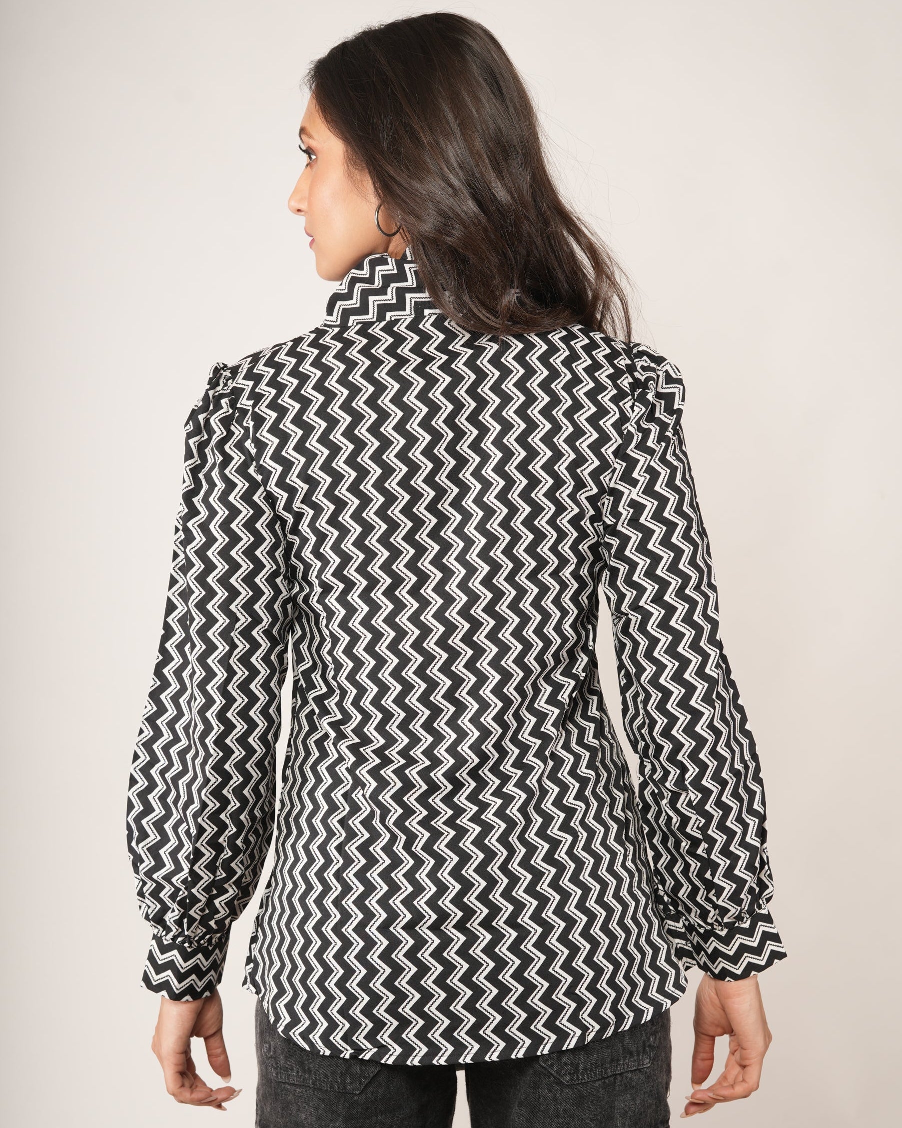 Person wearing a black and white patterned shirt with long sleeves.