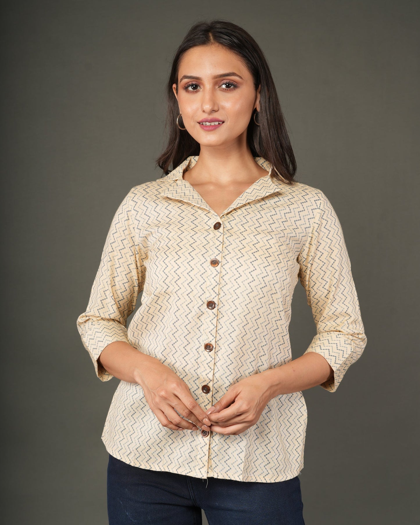 A woman modeling a beige and white zigzag patterned button-up shirt with dark brown buttons