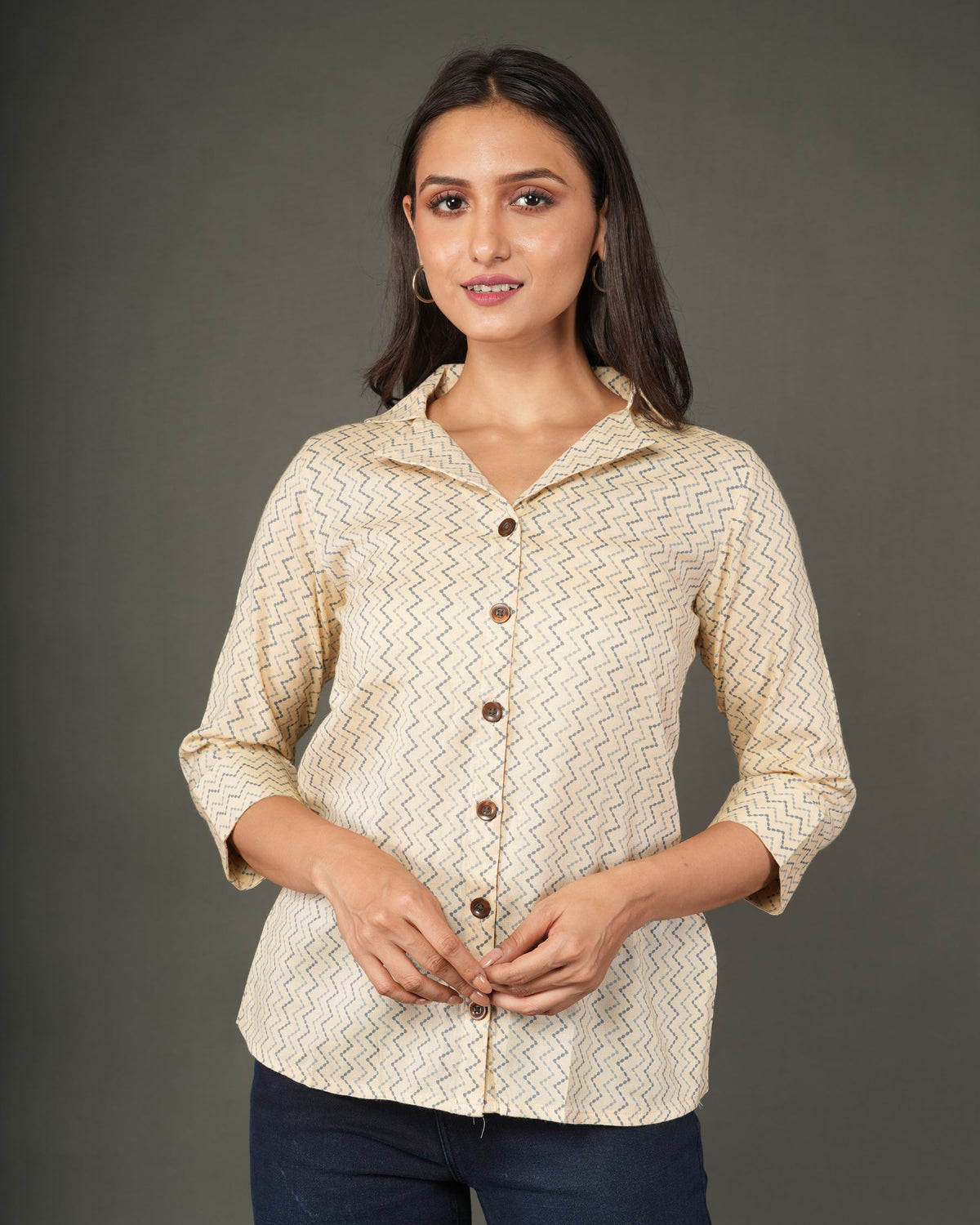 A woman modeling a beige and white zigzag patterned button-up shirt with dark brown buttons