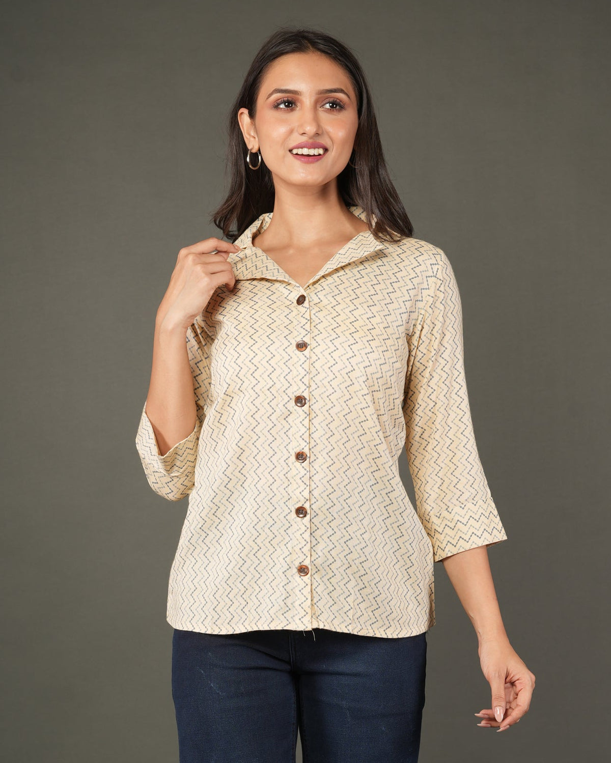 A woman modeling a beige and white zigzag patterned button-up shirt with dark brown buttons