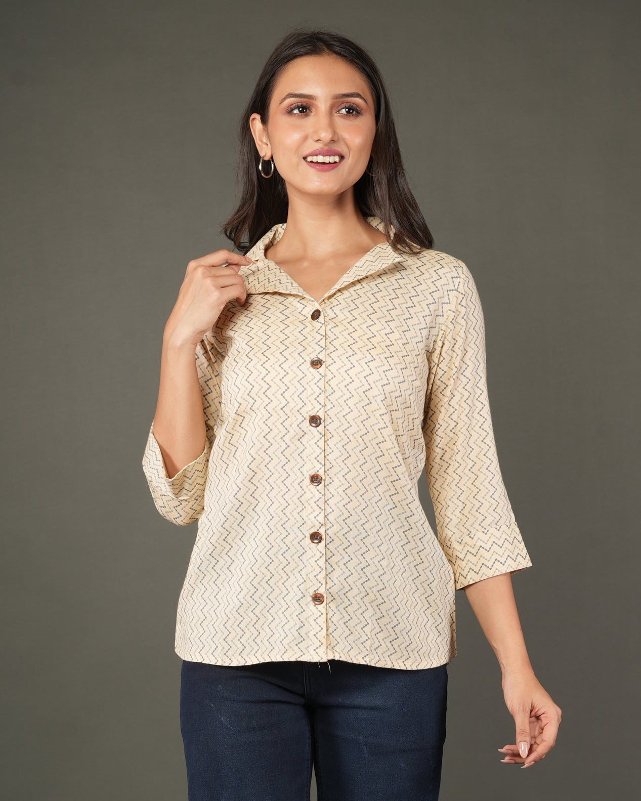 A woman modeling a beige and white zigzag patterned button-up shirt with dark brown buttons